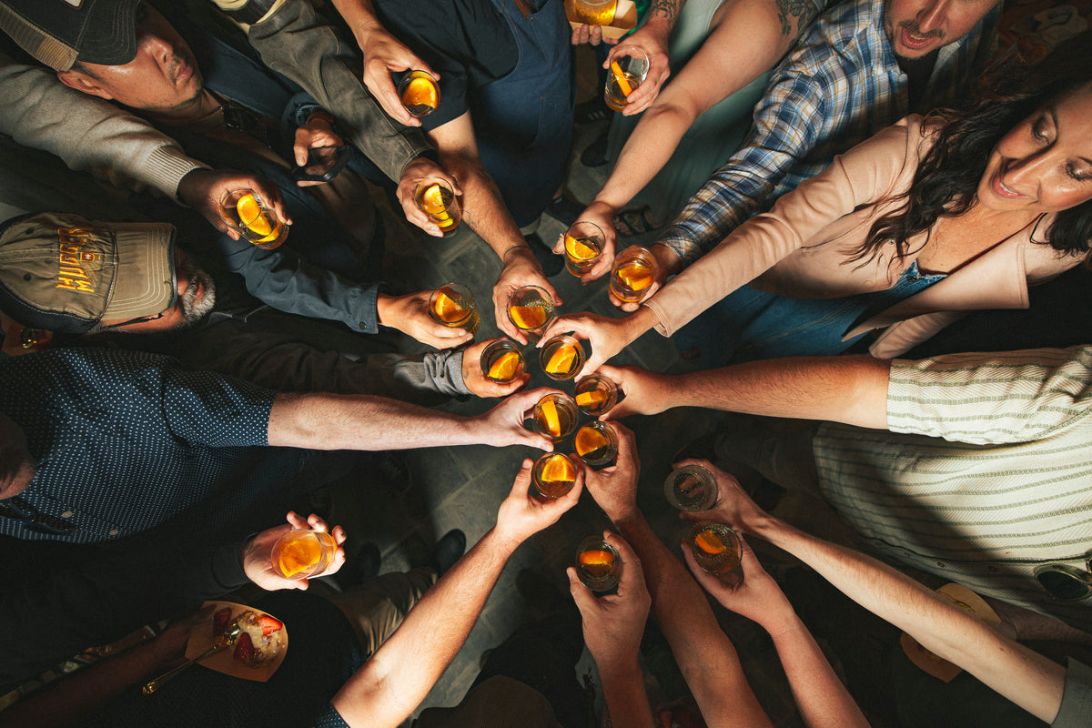 Group of people holding drinks together in a circle celebrating with a cheers
