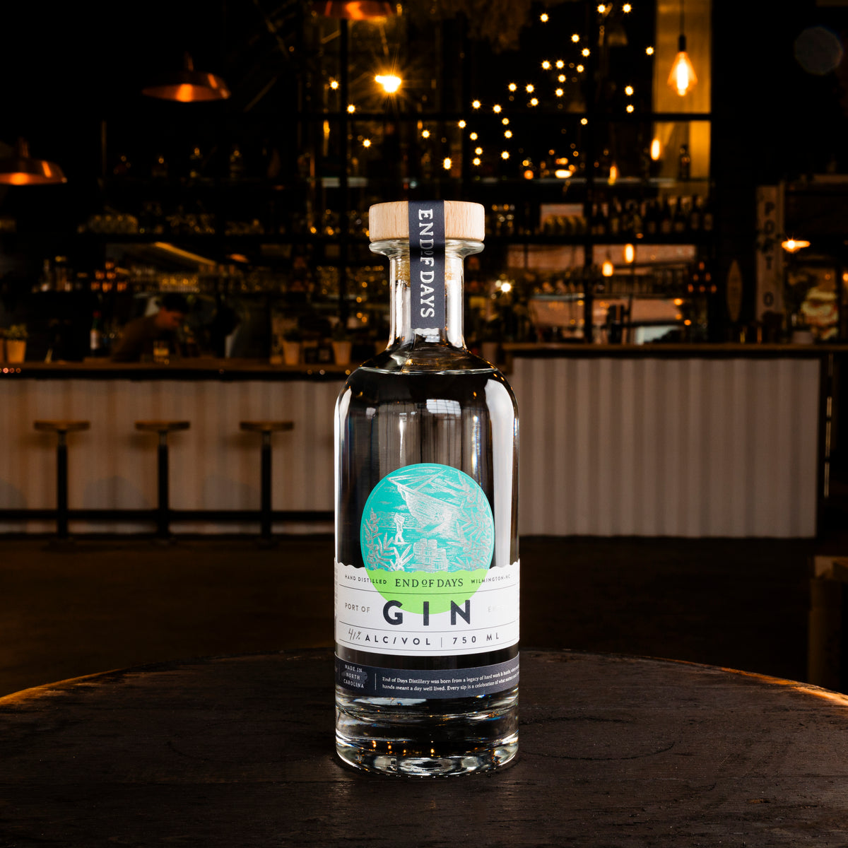 Port of Entry Gin bottle on a bar table with warm string lights in the background