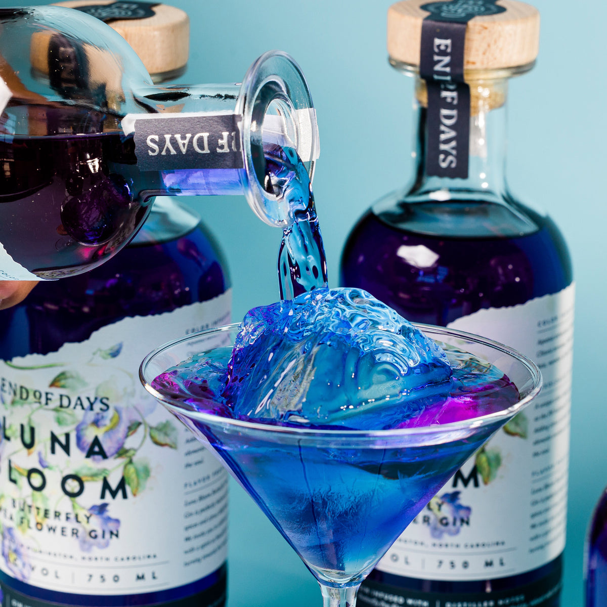 Luna Bloom gin poured over ice into a martini glass, swirling vivid blue and purple